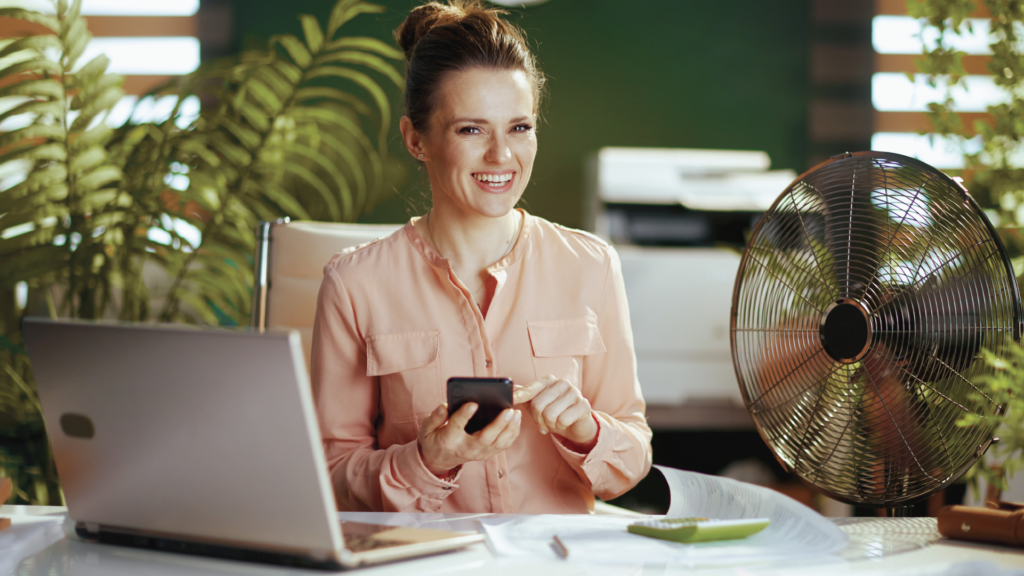 A happy female accountant using her phone and laptop.