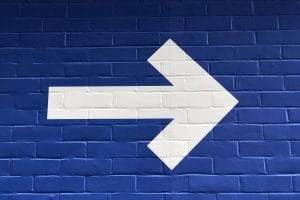 White Painted Arrow on a Blue Brick wall